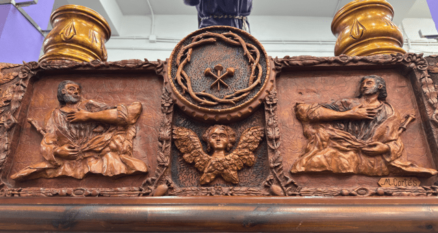 La parte frontal la preside el escudo de la cofradía que consta de los 3 clavos y la corona de espinas, justo debajo un ángel y sus lados dos apóstoles con cetros.