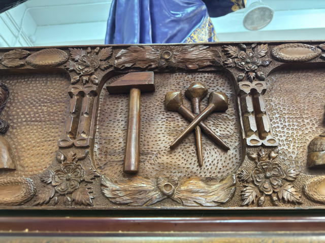 En la parte central el martillo y los tres clavos