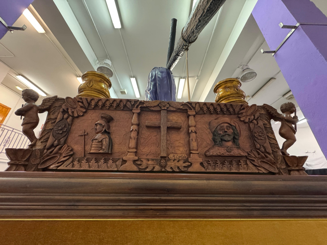 En la parte trasera vemos una cruz central, a su derecha el Apóstol Santiago y a su izquierda un soldado romano ( inspirado por su traje y lanza en los Putuntunes de Calanda)